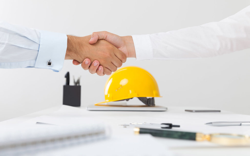 Two people shaking hands over a table with several items