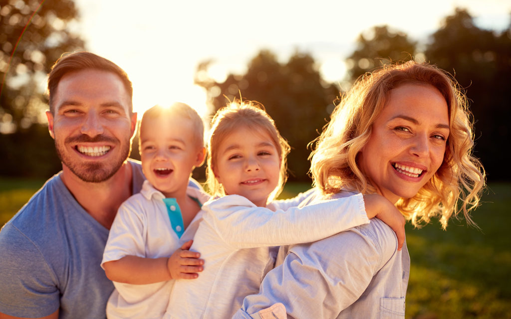 A family (father, mother, and two children) smiling at the camera