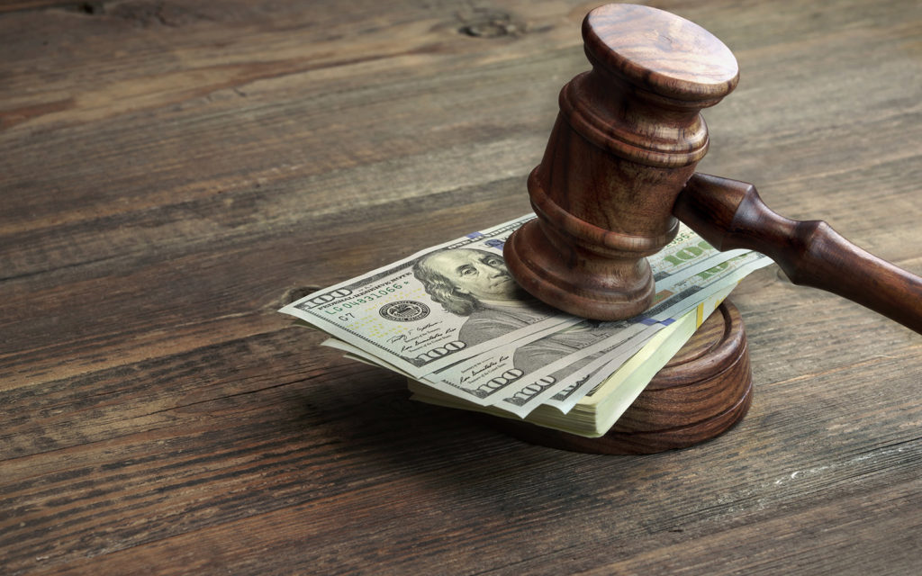 Table with a gavel with a stack of money between the gavel and its base