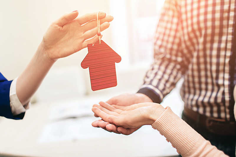 Woman handing a small representation of a house over to a couple