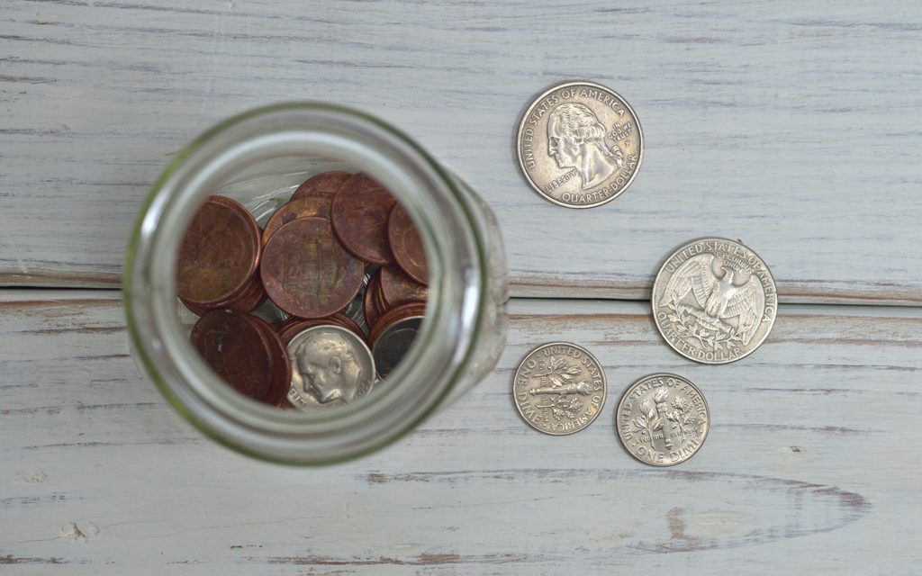 Wooden table with two quarters and dimes as well as a jar containing other change